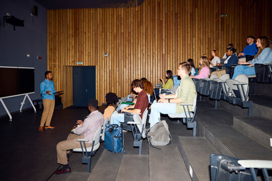 Young man is speaking to the students in the lecture room.