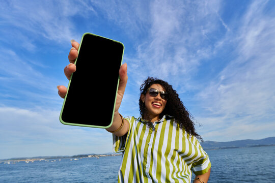 Woman holding smartphone with blank screen outdoors