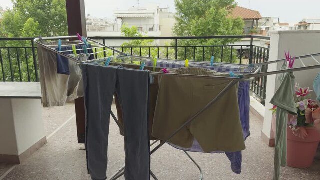 Clean Wet Laundry Hanging On Metal Drying Rack Stand On Outdoor Balcony Terrace. Domestic Garments Drying