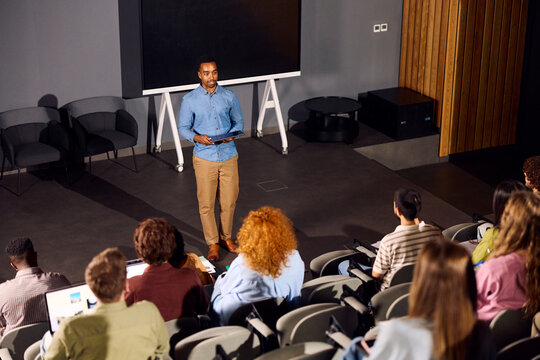 Young man is speaking to the class in the lecture room.