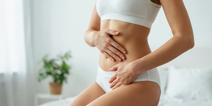 Woman touching her abdomen and pelvic area, experiencing discomfort or pain