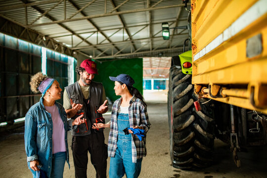 Farm team discussing tractor maintenance in barn workshop
