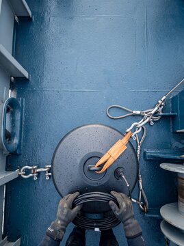 Top view of a maritime technician handling cables and scientific oceanographic equipment secured on a ship deck