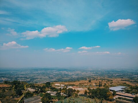Panoramic high angle view of rural landscape with rolling hills under a vibrant blue sky with clouds