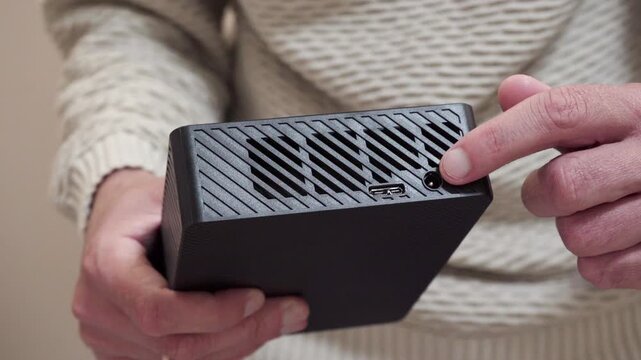 Man pointing finger at connectors and ports  on mini PC chassis, Demonstration of power and Type-C connectors on a portable device
