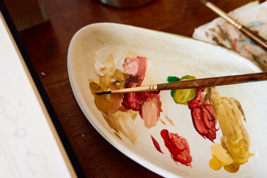 Artist paint palette with colorful paint mixtures and wooden brushes