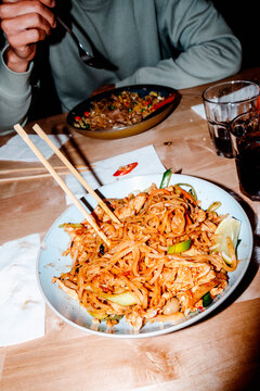 chicken pad thai on a restaurant table as a man eats stir-fried rice