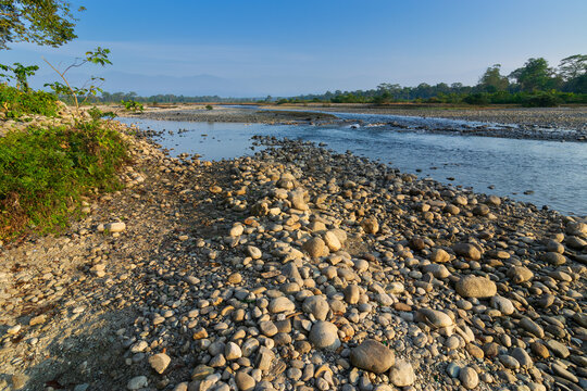 Murti river in the morning, riverbed in foreground with flowing water and stones. Scenic beauty of Dooars landscape, West Bengal, India. Dooars is popular tourist destination for natural landscapes.