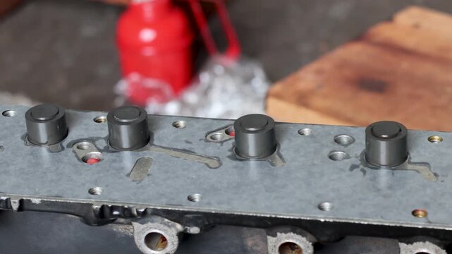 Close-up of a technician hand installing a metal valve piston with dual coil springs into a hydraulic control body unit.