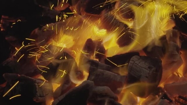 Glowing charcoal embers with rising sparks and intense heat for barbecue background, fire flames