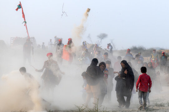 Okara, Pakistan - 13 March 2024: View of pilgrims walking through a dusty path during the annual Urs festival at the shrine of Hazrat Daud Bandagi Kirmani, with people in traditional attire.