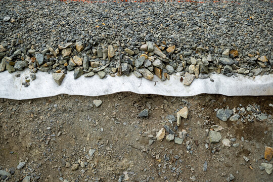 Road construction showing gravel, geotextile fabric, and soil layers