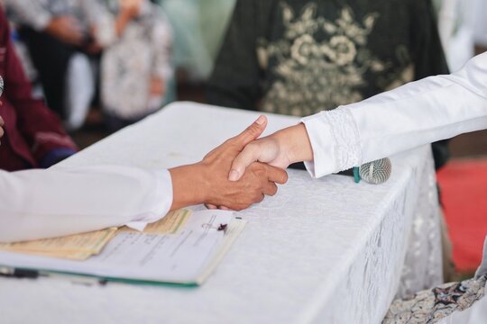 Close up of traditional Islamic wedding handshake between bride and groom with soft bright natural indoor lighting