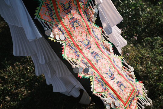 Laos - 31 December 2024: View of traditional Hmong tribe clothing featuring intricate colorful embroidery, geometric patterns, and silver coin embellishments on a black fabric base.