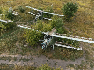 Abandoned AN-2 aircrafts with rusting in overgrown summer airfield aerial view