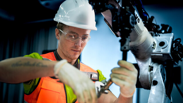 An engineer programs or repairs a high-tech industrial robot. This smart factory uses AI-driven automation for advanced manufacturing or microchip production.