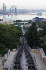Fototapeta premium Captivating view of railway tracks leading towards a stunning waterfront cityscape in Baku at twilight