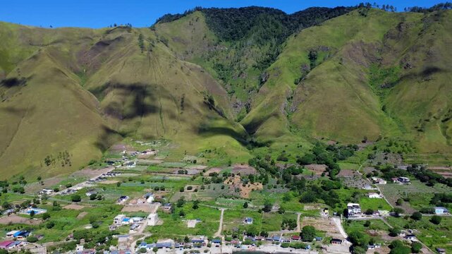 Aerial view of Lake Toba and the village of Paropo nestled among lush green mountains and terraced fields in Paropo, Sumatera Utara, Indonesia.