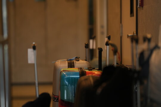 A hotel bellboy with guest luggage, lifting suitcases onto a brass luggage trolley in a luxury hotel lobby by the luggage cart, in a stylish contemporary hospitality setting.