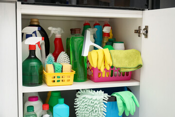 Different cleaning products and supplies in cabinet indoors, closeup