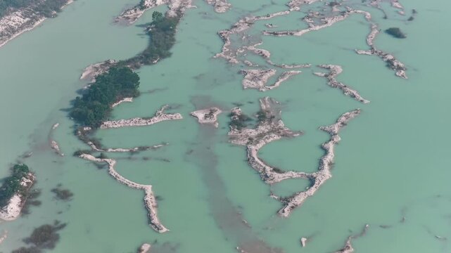 Overhead perspective of green water and sandy terrain patches in a rural region of Indonesia
