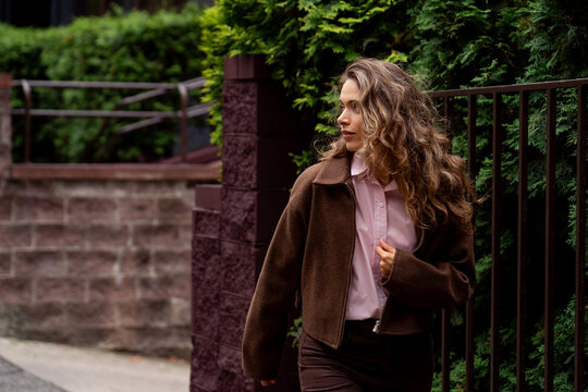 Attractive young woman with long curly hair walking outside