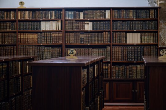 Coimbra, Portugal - 27 August 2026: View of the historic Biblioteca Joanina featuring rows of antique leather-bound books on wooden shelves and numbered study tables.
