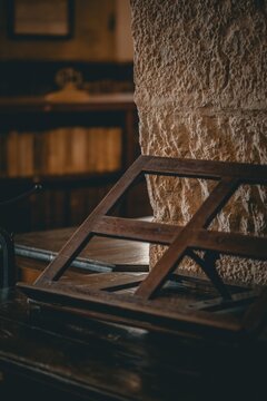 Coimbra, Portugal - 27 August 2026: View of a wooden book stand inside the historic Biblioteca Joanina, featuring textured stone walls and blurred bookshelves in the background.