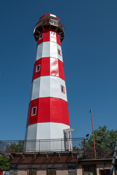 Newly painted red and white lighthouse in midday sunlight.