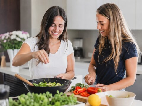 Zwei Frauen bereiten gemeinsam frische Speisen in einer modernen K&uuml;che zu. Authentische Alltagsszene mit regionalem Genuss, Kochen und kulinarischem Tourismus in Italien.