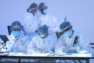 A semiconductor inspection team raise a wafer to the light for quality control in a microchip...