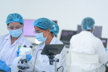 Laboratory coworkers examine colourful red and green reagent tubes in a well-lit research...