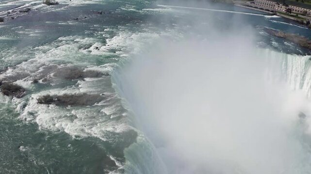 Aerial view of the powerful cascading waters of Niagara Falls with mist rising from the river in Niagara Falls, Ontario, Canada.
