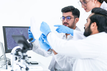 A scientist in safety glasses inspects a laboratory sample with focus in a bright white research...