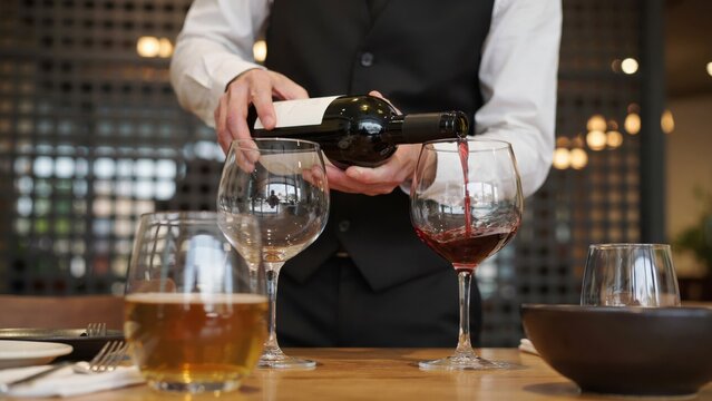 Waiter pouring red wine into glass in restaurant