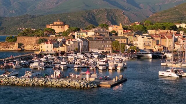 White catamaran entering Saint Florent marina in Corsica France. Luxury yachting lifestyle 70mm telephoto aerial drone stock video 4K