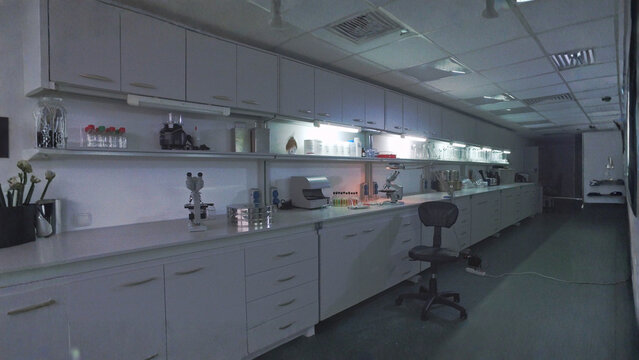 Dimly Lit Modern Scientific Research Laboratory Interior with Long Workbench and Overhead Cabinets