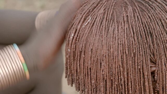 Women in the Hamar tribe doing their hair in the traditional manner with red clay.