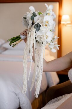Bride holding cascading white orchid wedding bouquet side view