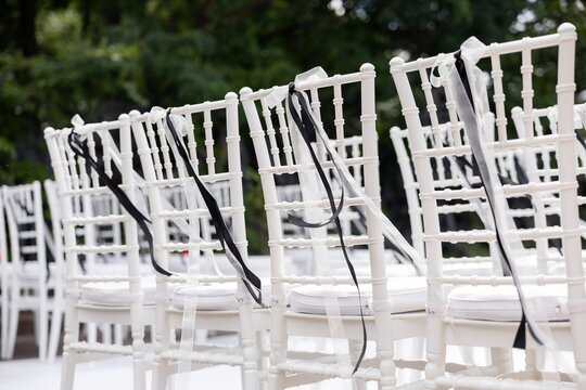 White chiavari chair decorated with black and white ribbon
