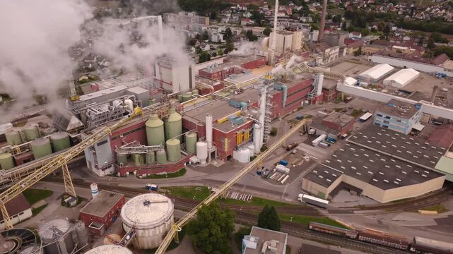 Aerial view following a truck entering a pulp and paper mill as steam drifts into frame, Gratkorn, Styria, Austria