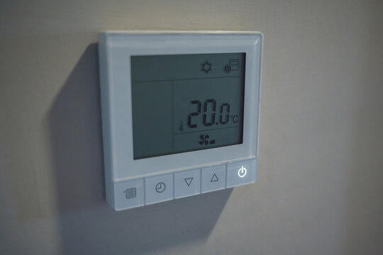 Digital air conditioning thermostat showing 20 degrees, cooling temperature control and energy saving concept
