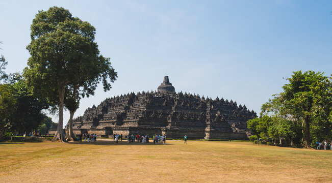 Panoramic Wide View of Ancient Borobudur Temple Across Open Park Grounds Framed by Trees in Central Java near Yogyakarta Indonesia