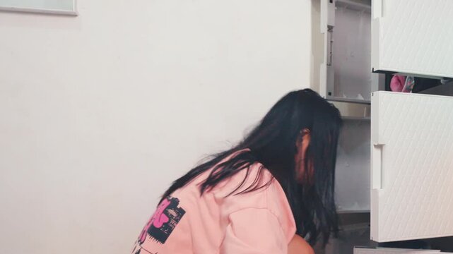 Young Woman Organizing Clothes in a Plastic Cabinet in Her Room