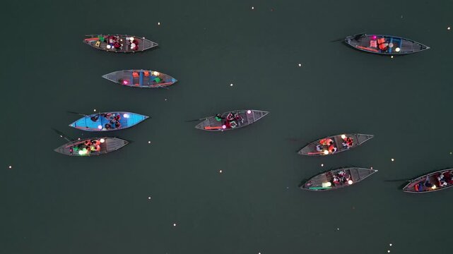 Aerial view of traditional wooden boats with glowing lanterns floating on the river at night in Hoi An, Da Nang, Vietnam.