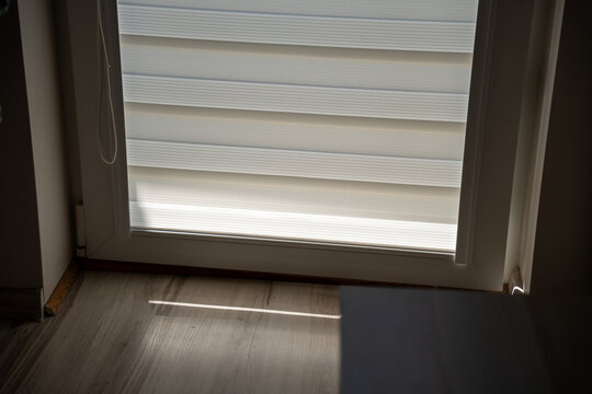 Sunlight streaming through a zebra blind covered window in a home interior, concept of natural light and window treatment
