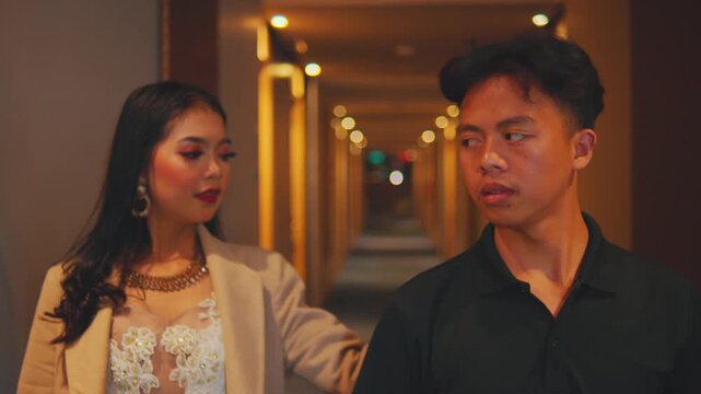 Woman Gestures "Shh" to Man at Hotel Room Door and Walks Away