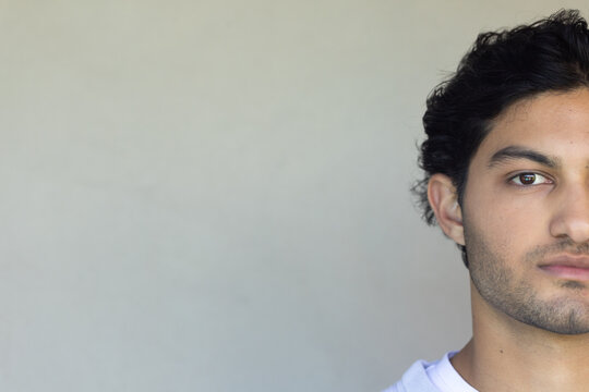 Adult male posing on right side in studio against light-gray wall with white T-shirt, copy space