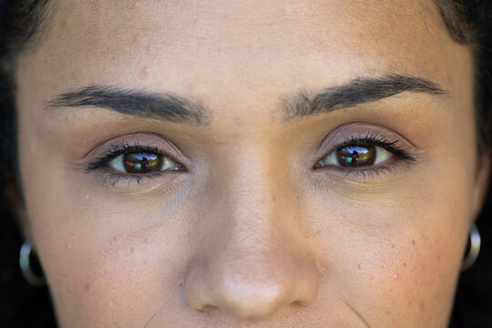 African American woman showing subtle eye makeup in studio closeup with silver hoop earrings