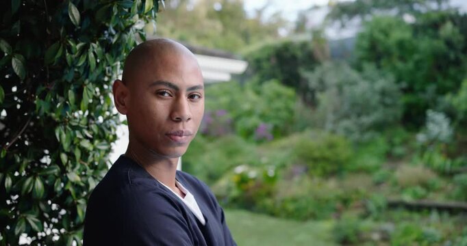 Asian adult man standing with arms crossed, responding to camera moving closer at house entry hedge